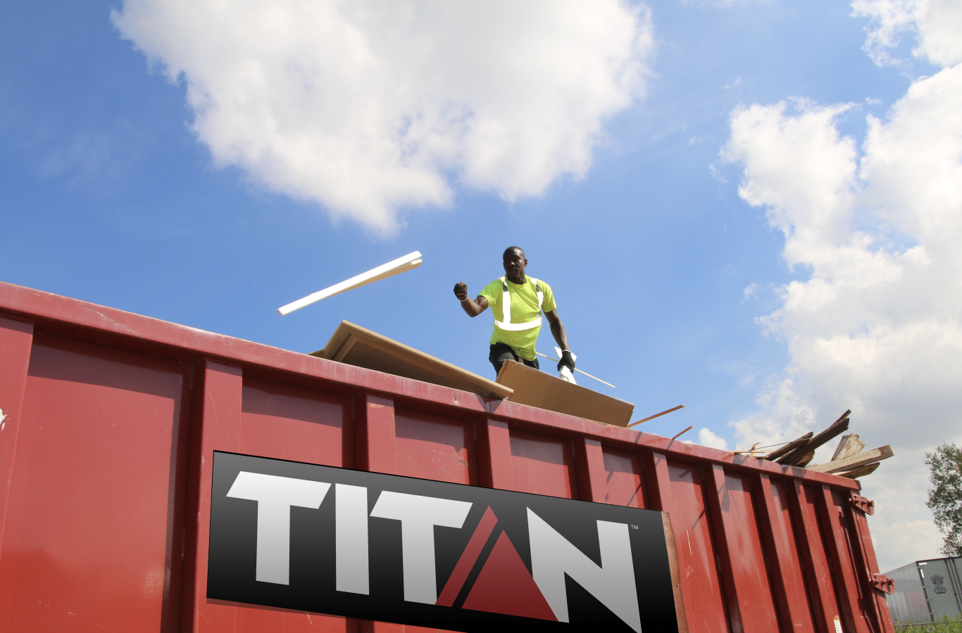 Titan Dumpster with man tossing waste in it.