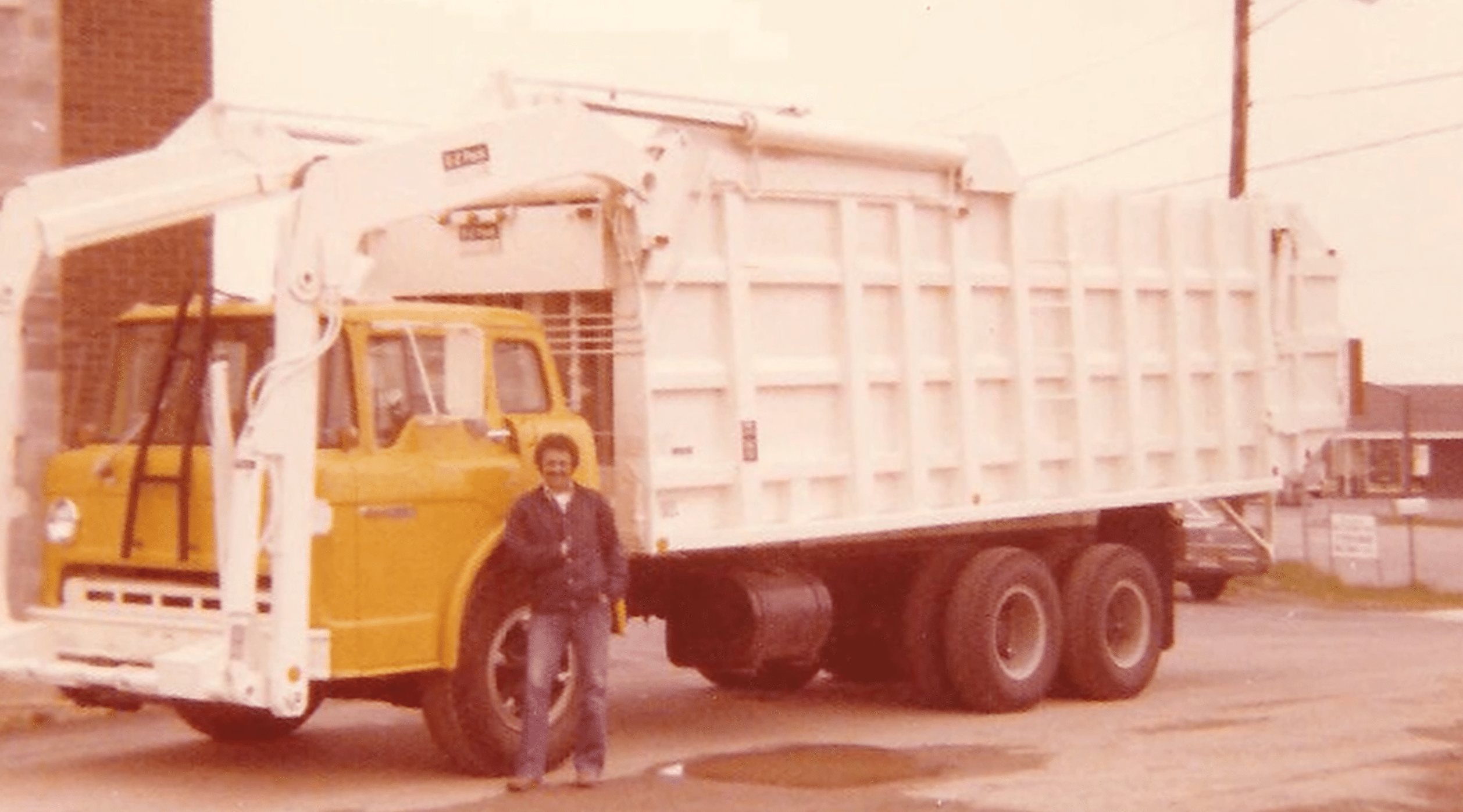 Old Garbage truck with a Rizzo standing infront of it.